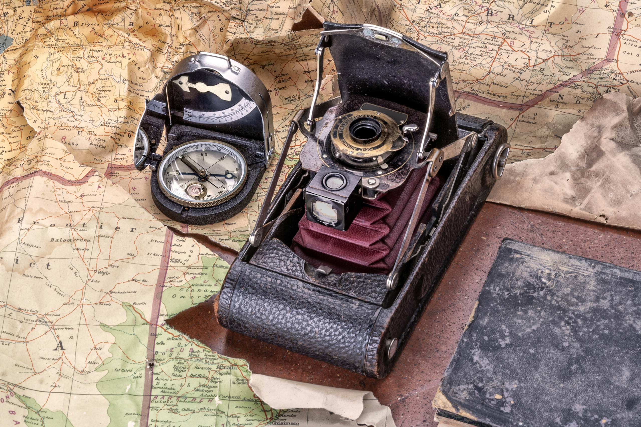 Old photo camera and compass on an old set of maps
